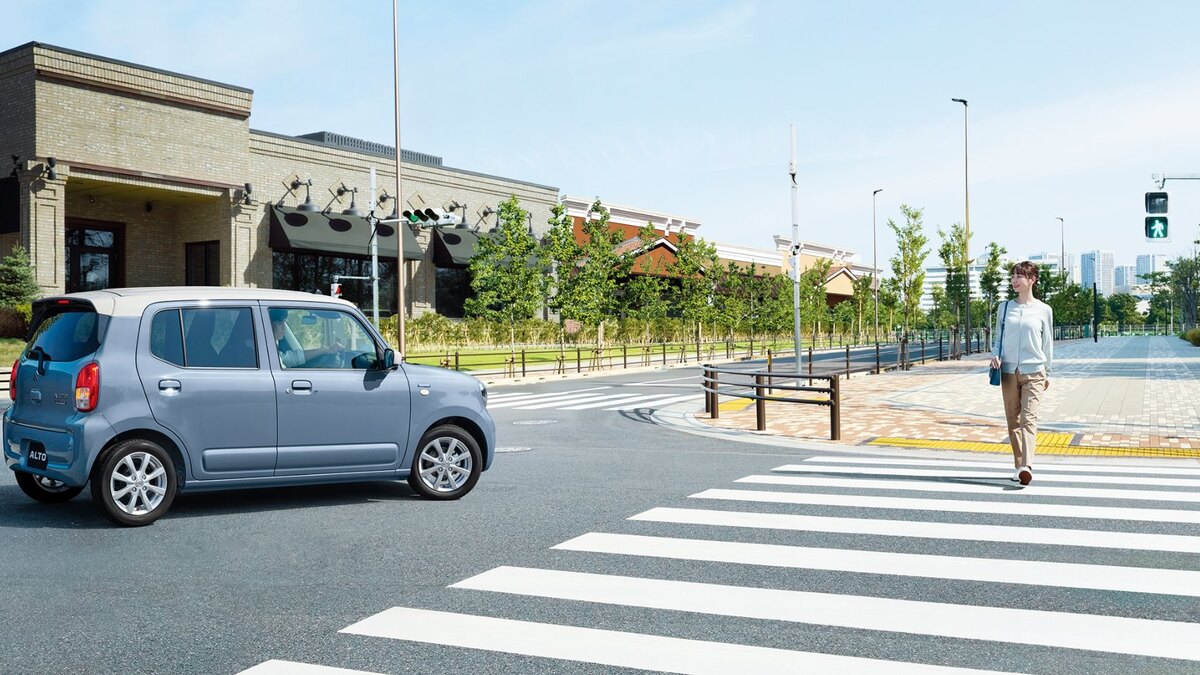 横断歩道の手前にいるアルト HYBRID Xの側面